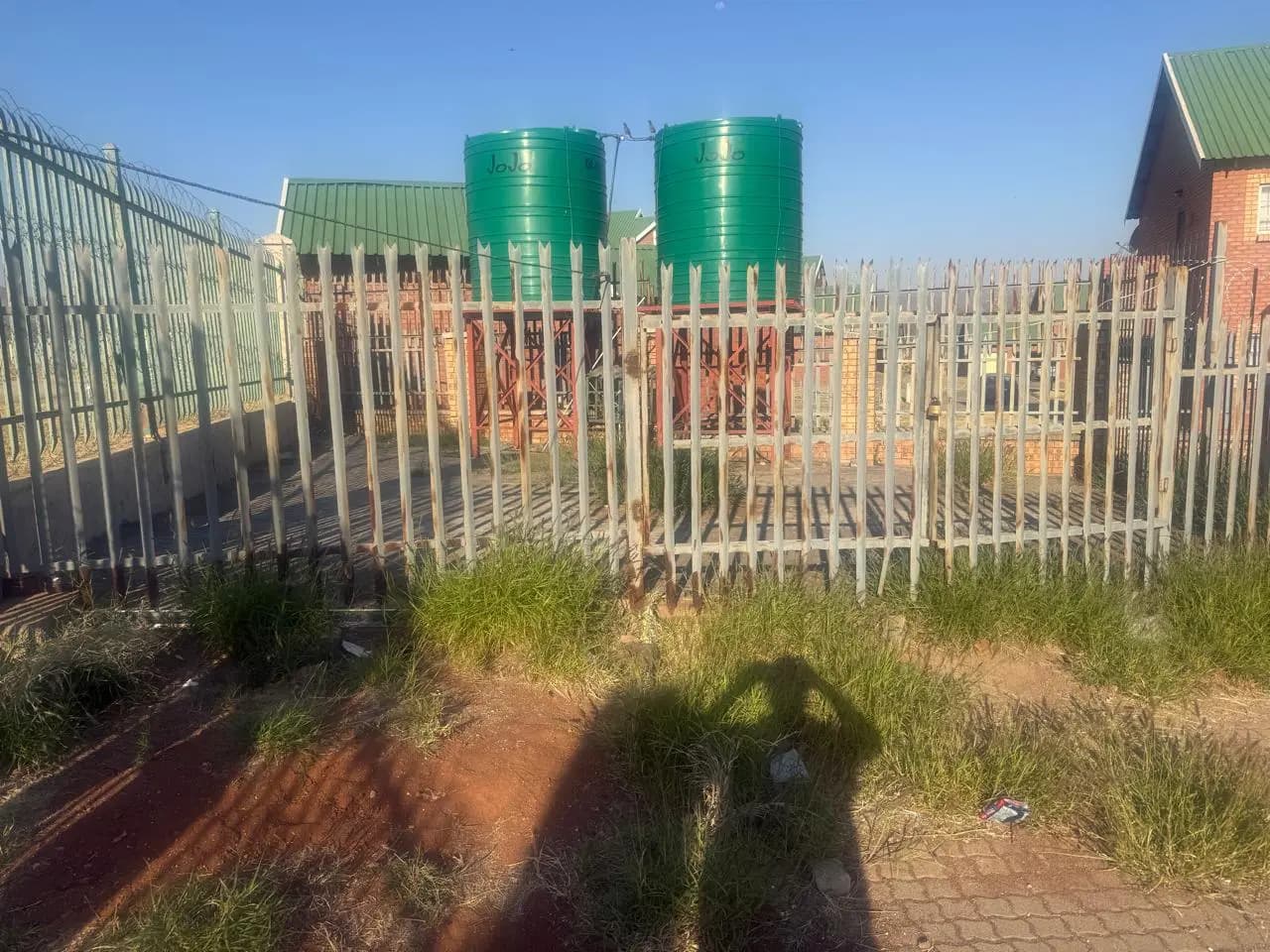 Large green water tanks installed at a fenced facility