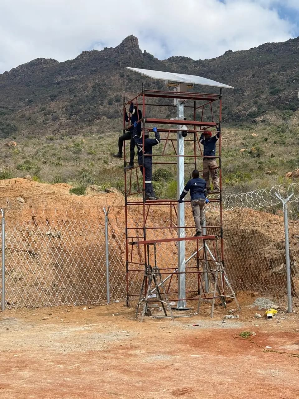 Technicians installing surveillance equipment on a raised structure